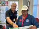 ARRL Puerto Rico Section Manager Carmen Greene, KP4QVQ (R), and PREMB Zone 5 Director A. Trabal (L) in Mayagüez study a coastal map of Puerto Rico while monitoring the tsunami bulletin alerts to pass on amateur radio nodes.